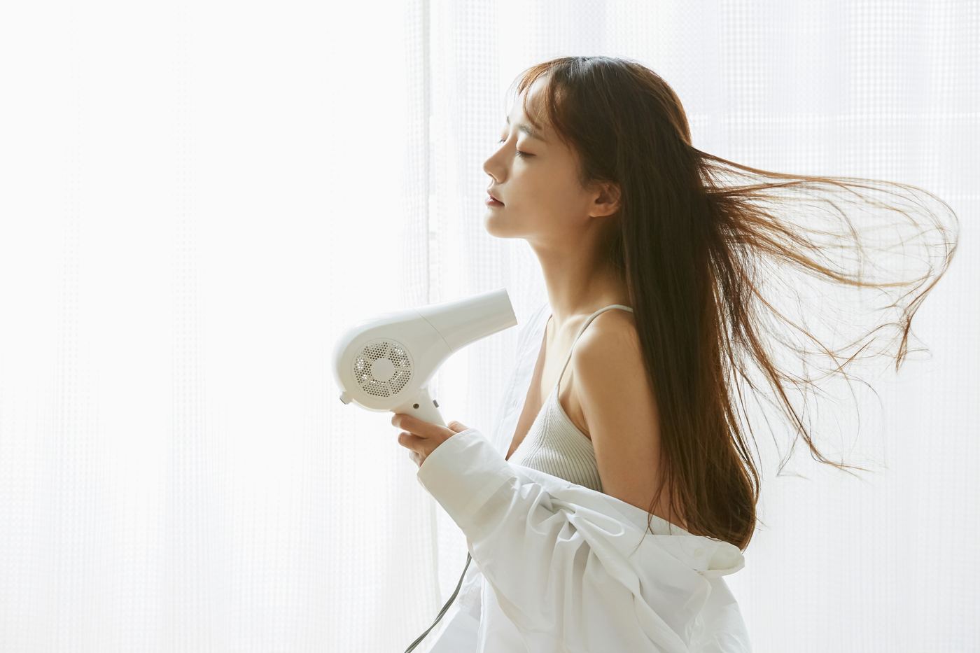 ドライヤーで髪を仕上げる女性